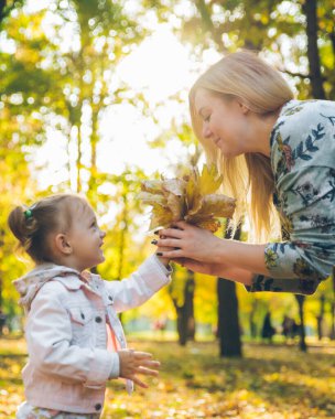 Mather ve küçük kızı sonbahar parkında oynuyorlar.