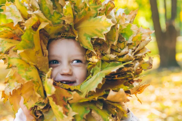 Niña jugando con hojas de arce corona de flores — Foto de Stock