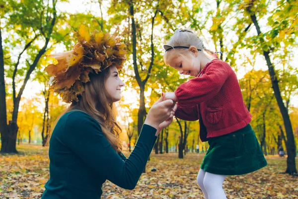 Junge Mutter bastelt Ahornblatt-Kranz für kleine Tochter — Stockfoto