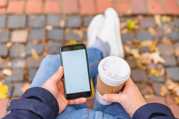 No face man sitting on the bench at city park drinking coffee surfing on phone — Stock Photo, Image