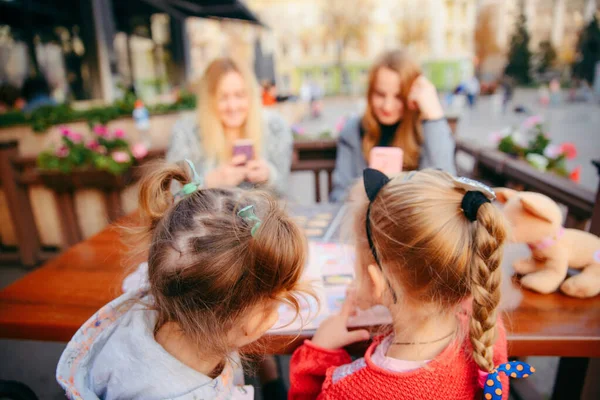 Kleines Mädchen sitzt im Café und wählt Essen aus der Speisekarte — Stockfoto