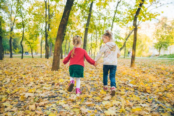 Duas meninas namoradas jogando no outono parque da cidade de mãos dadas — Fotografia de Stock