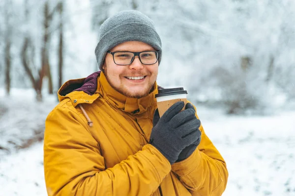 Retrato del hombre sonriente fuerte bebiendo café para ir en el parque de la ciudad nevada — Foto de Stock