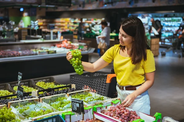 Kvinna som köper druvor i butik — Stockfoto