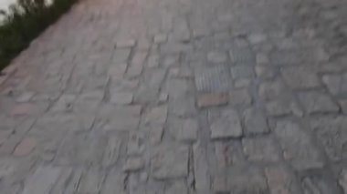 İlk bakışta insan bacakları çıplak ayakla eski bir kaldırım taşının yanından geçiyor. 