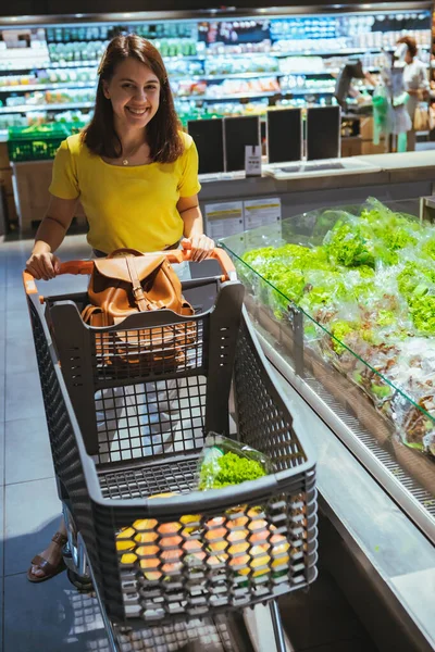 Жінка бере салат з полиці продуктового магазину — стокове фото