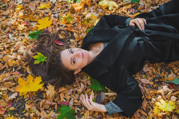 Жінка лежить на землі в осінньо-жовтому листі — стокове фото