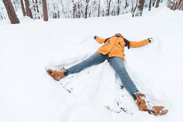 Молодая взрослая женщина делает снежного ангела — стоковое фото