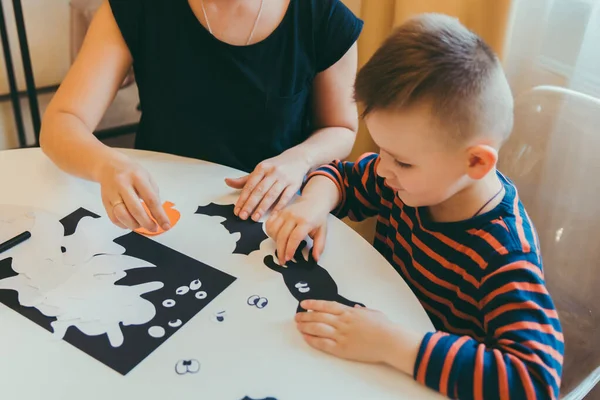 Young mother with toddler son making craft spiders for halloween holiday — Stock Photo, Image