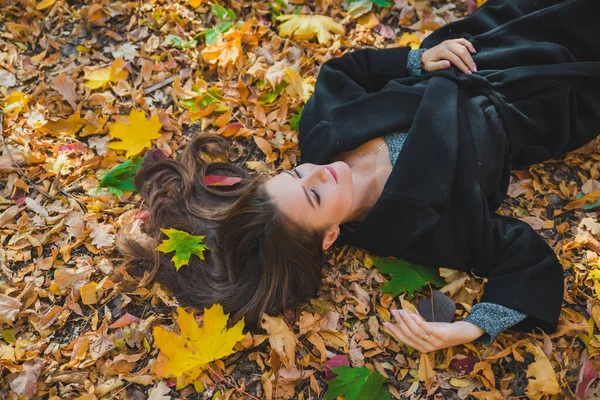 Woman laying on the ground in autumn yellow leaves — Stok fotoğraf