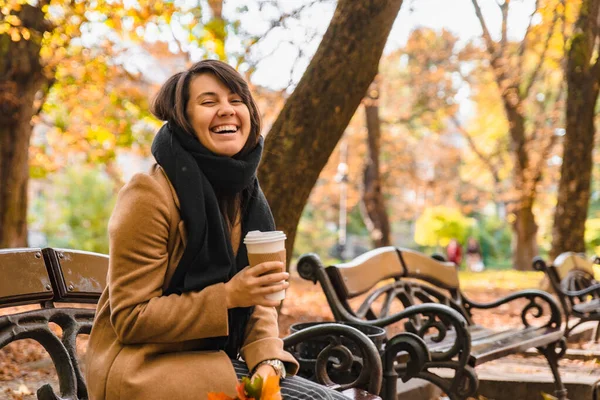 Mulher sentada no banco no outono parque da cidade bebendo café — Fotografia de Stock