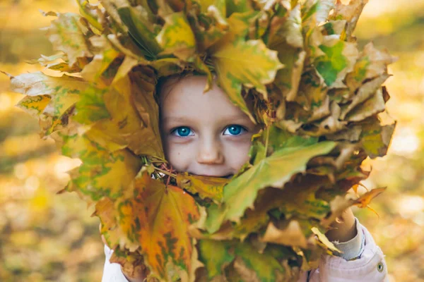 Kleines Kleinkind spielt mit Ahornblätterkranz — Stockfoto