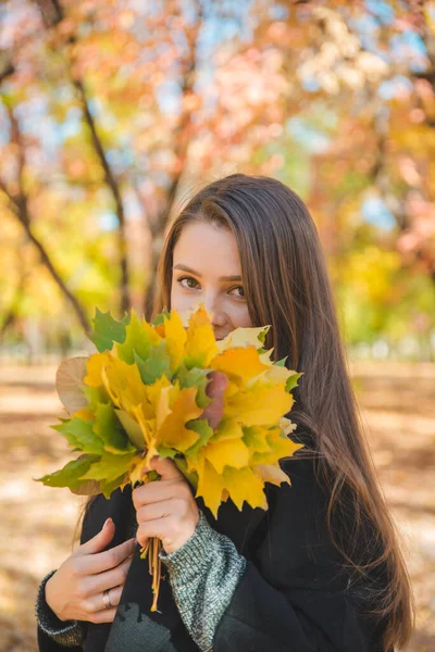 Młoda ładna kobieta zabawia się z żółtym liściem klonu — Zdjęcie stockowe