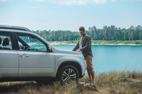 Auto-Reise-Konzept Mann sieht den Mann auf SUV-Motorhaube See im Hintergrund — Stockfoto