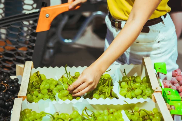Женщина рука берет виноград из коробки на рынке магазина — стоковое фото
