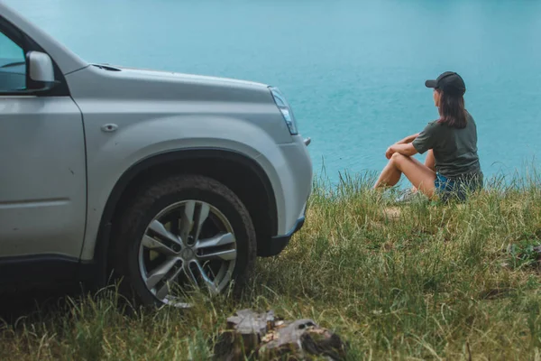 Frau sitzt am Rand und genießt Blick auf den See — Stockfoto