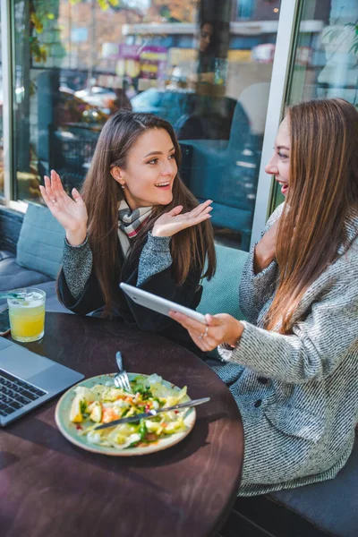 Two young adult women have meeting in outdoors cafe working on laptop — Stock Photo, Image