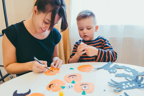 Young mother with toddler son making craft pumpkins for halloween holiday — Stock Photo, Image
