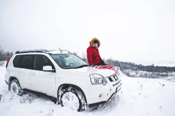 Uomo seduto sul cofano della macchina del SUV con bandiera degli Stati Uniti. concetto di viaggio in auto — Foto Stock