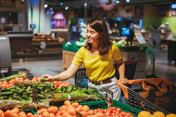 妇女选择黄瓜从商店货架杂货店购物 — 图库照片