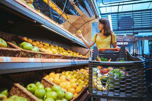 Kobieta biorąc pomarańcze z półki sklepowej supermarket — Zdjęcie stockowe