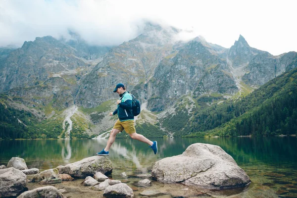 Silný muž skok z skály na pláži jezera v horách — Stock fotografie