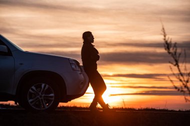 Kadın arka planda gün batımına yakın duruyor. Yol gezisi
