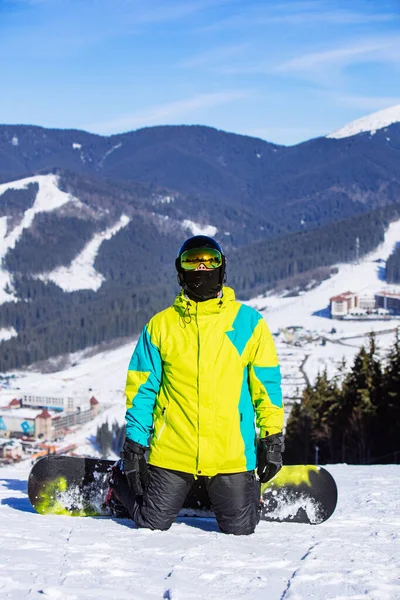 Muž na vrcholu kopce se snowboardem ve slunečný den — Stock fotografie