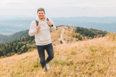 Sırt çantalı bir adam sonbahar dağlarında yürüyüş yapıyor.