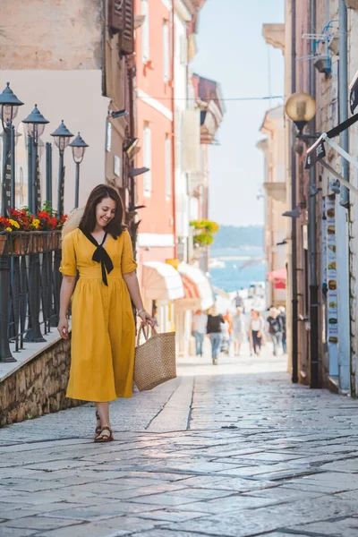 Jovem mulher bonita em vestido amarelo andando por pequenas ruas da cidade porrec mar no fundo — Fotografia de Stock