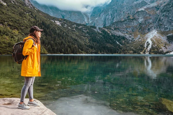 Mujer en impermeable amarillo en la playa del lago en el parque nacional de Tatra — Foto de Stock