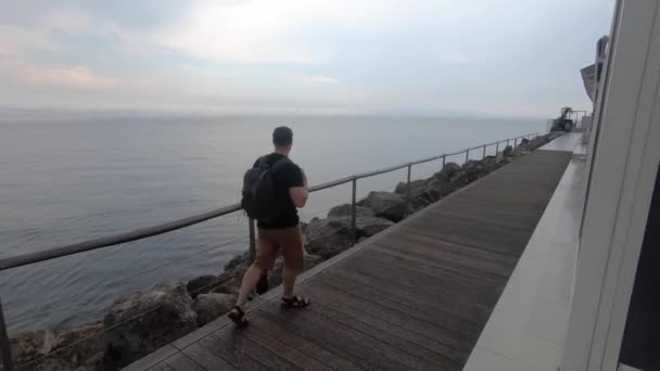 Man Met Rugzak Wandelen Door Zee Kade Onder Regen Zomer — Stockvideo