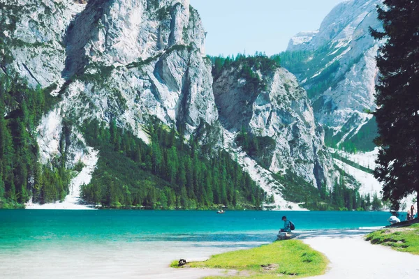 Чоловік сидить на пляжі гірського озера, насолоджуючись видом — стокове фото