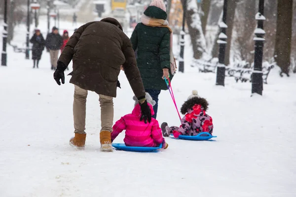 Niños deslizándose en la colina de invierno en el parque de la ciudad — Foto de Stock