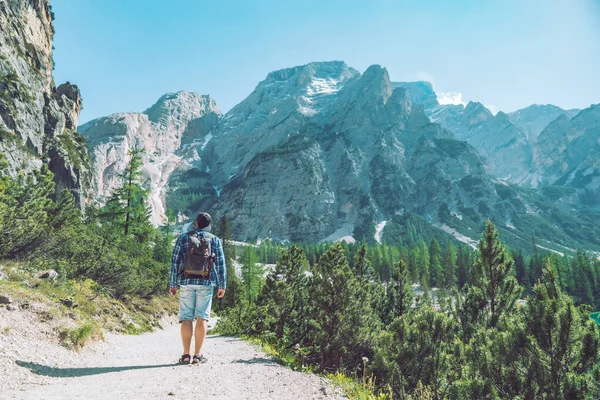 Joven con mochila caminando por el sendero de las montañas en día soleado — Foto de Stock