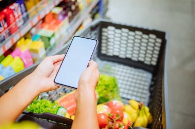 arka planda boş boş beyaz ekran alışveriş sepeti ile telefon