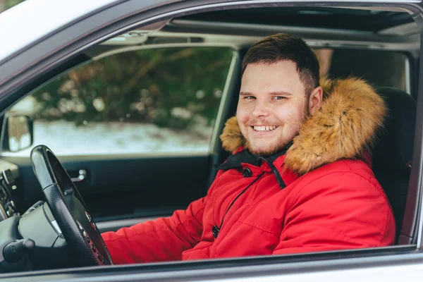 Человек в машине в зимнее время смотрит в камеру — стоковое фото