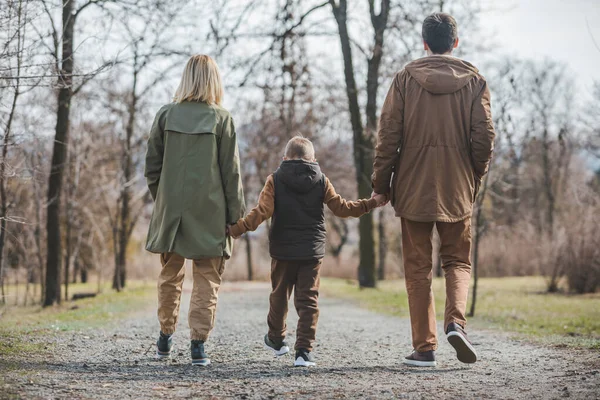 Молодая красивая семья прогуливаясь взявшись за руки в городском парке — стоковое фото