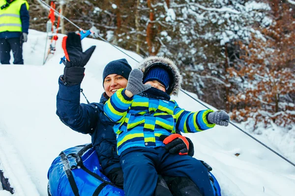 Father with son on snow tube. pull up to hill — Stok fotoğraf