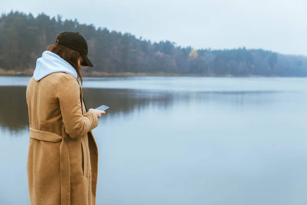 Donna in abito autunno in piedi al bordo guardando nebbia lago — Foto Stock