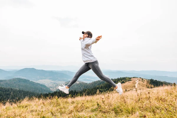 Donna che salta alla vetta della montagna bella vista della valle sullo sfondo — Foto Stock
