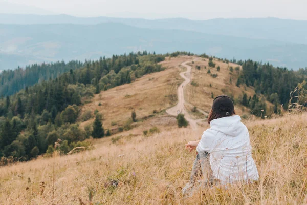 Donna seduta a terra guardando montagna escursionismo concetto — Foto Stock