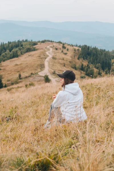 Жінка сидить на землі, дивлячись на гори концепція пішохідного туризму — стокове фото