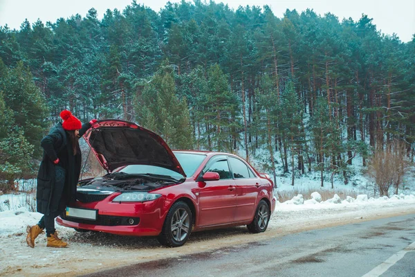 Mujer mirando motor roto coche en invierno carretera lado — Foto de Stock