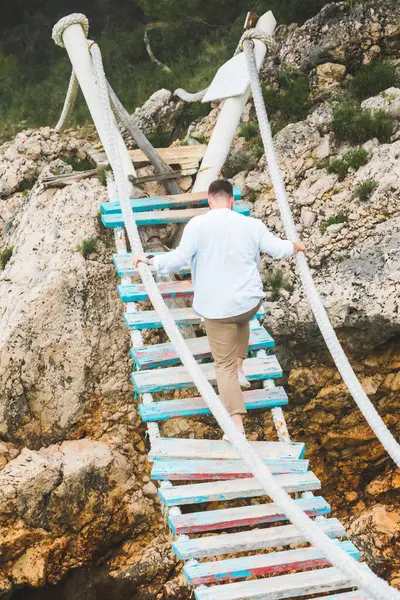 Homem andando por ponte suspensa cruzar o mar — Fotografia de Stock