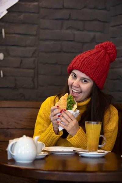 Mujer feliz joven en traje de invierno sombrero rojo sentado en la cafetería beber té caliente — Foto de Stock