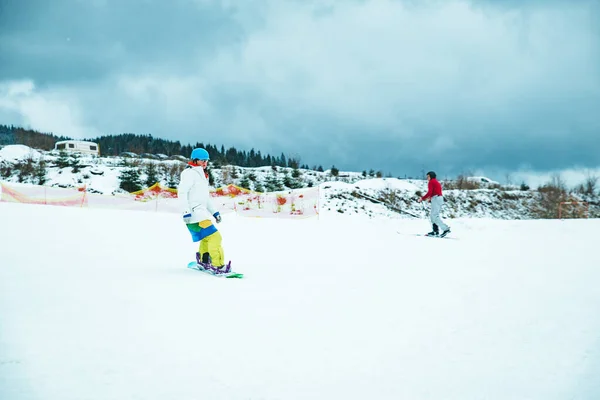 Homem de traje colorido no snowboard. montanhas nevadas no fundo — Fotografia de Stock