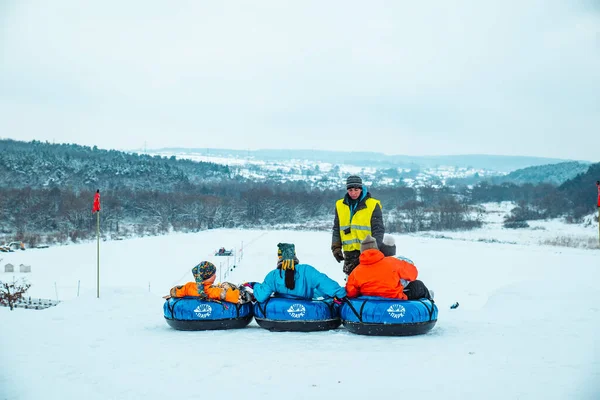 LVIV, UCRÂNIA - 7 de janeiro de 2019: passeio em família pela colina nevando com tubo de neve — Fotografia de Stock