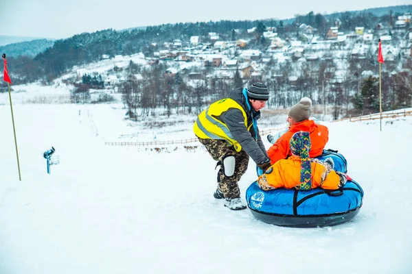 Lviv, ukraine - 7. januar 2019: Familienfahrt durch schneebedeckten Hügel mit Schneeschlauch — Stockfoto