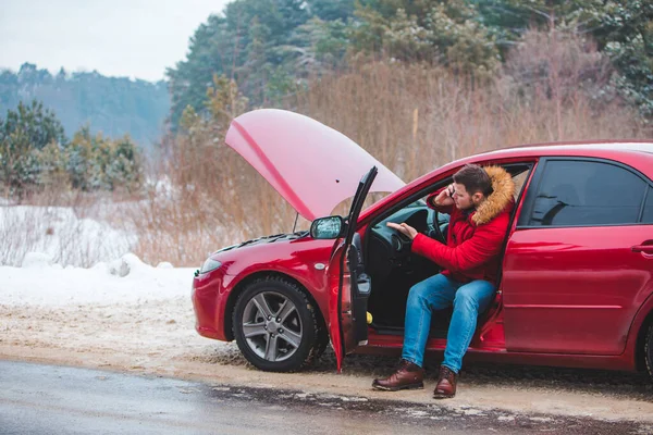 Um homem sentado no carro a pedir ajuda. quebrar na pista de inverno — Fotografia de Stock